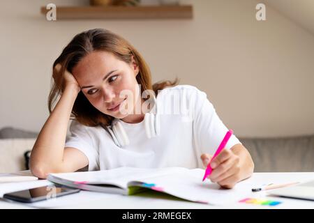 Tired female university student doing homework at home. Stock Photo