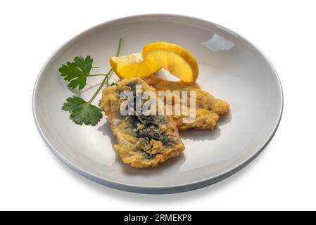 Batter-fried blue sardine fish with parsley leaves and lemon slices in a dish isolated on white with clipping path included Stock Photo