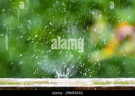 Raindrops fall on a garden table, water splashes, Germany, Europe Stock Photo