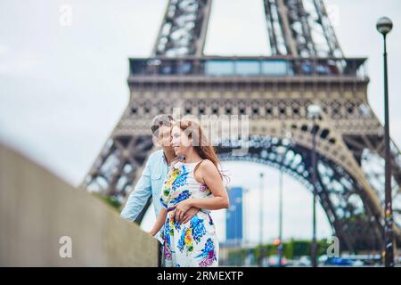 Happy romantic couple near the Eiffel tower in Paris, Tourists enjoying their vacation to France Stock Photo