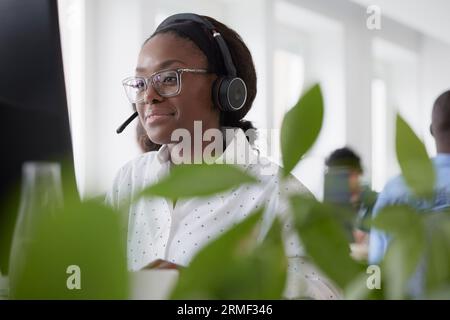Mid adult woman using headset while sitting in office Stock Photo