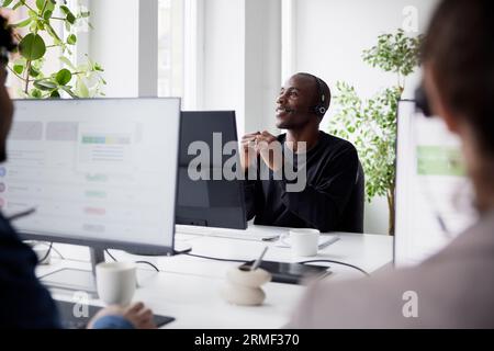 Smiling mature businessman using headset while sitting in office Stock Photo