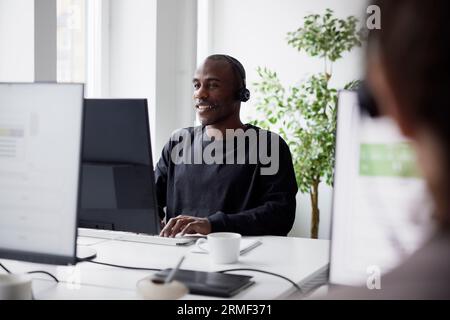 Smiling mature businessman using headset and desktop PC  in office Stock Photo