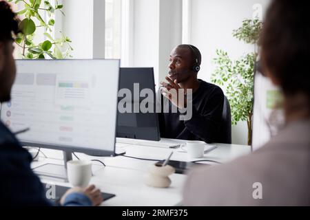 Smiling mature businessman using headset while sitting in office Stock Photo