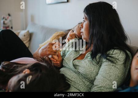 Loving mother and daughters relaxing on sofa at home Stock Photo