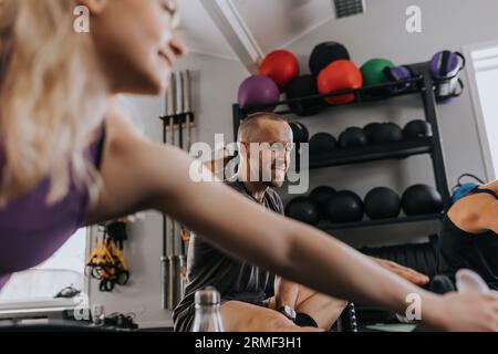 Smiling man sitting on floor and looking away during fitness class Stock Photo