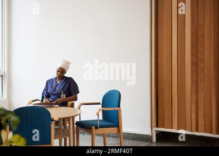 Female doctor sitting at table and taking notes Stock Photo