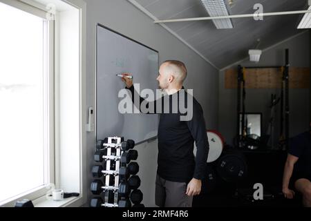 Man writing on whiteboard in gym Stock Photo