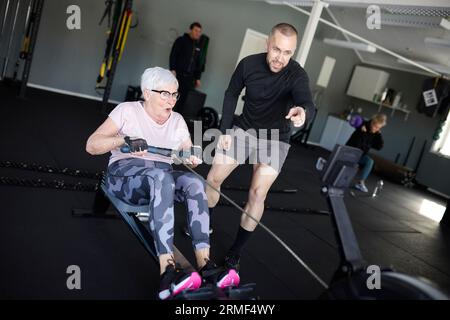 Coach assisting to senior woman exercising in gym Stock Photo