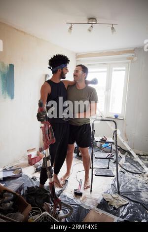 Smiling male homosexual couple looking at each other during apartment renovation Stock Photo