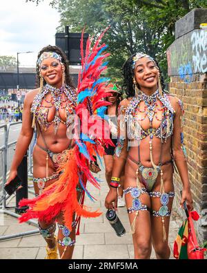 London, UK. 28th Aug, 2023. Two participants hurry to join their group for the start of the parade. Participants in the main carnival parade have fun on Carnival Monday. Up to two million people are expected to celebrate the carnival this Bank Holiday Weekend participating or watching along the carnival route, at sounds systems, stalls and venues. Credit: Imageplotter/Alamy Live News Stock Photo