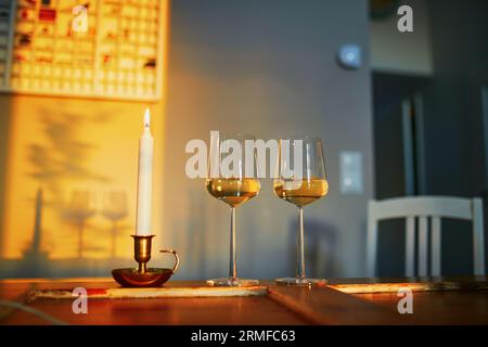 Two glasses of white wine and candle in beautiful evening light Stock Photo