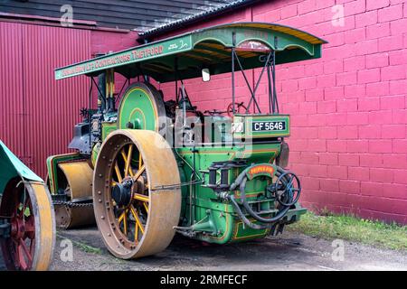 Bressingham, Norfolk, UK – August 21 2023. Traditional steam roller parked up outside a storage shed of a transport museum Stock Photo