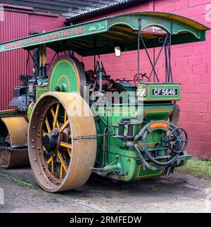 Bressingham, Norfolk, UK – August 21 2023. Traditional steam roller parked up outside a storage shed of a transport museum Stock Photo