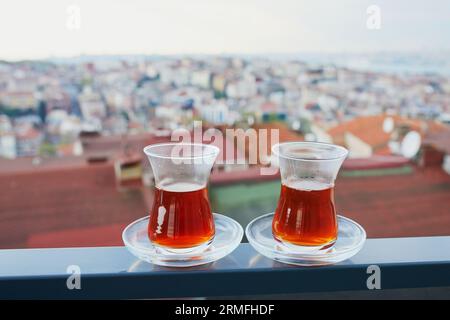 Two Turkish glasses in form of a tulip filled with hot black tea with view to the roofs of Uskudar district on Asian side of Istanbul, Turkey Stock Photo