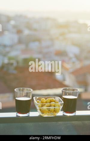 Two glasses of red wine and green marinated olives with view to the roofs of Uskudar district on Asian side of Istanbul, Turkey Stock Photo