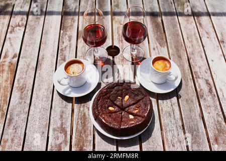 Two glasses of Madeira wine, two cups of fresh espresso coffee and traditional Portuguese honey and nut dessert bolo de mel in cafe Stock Photo