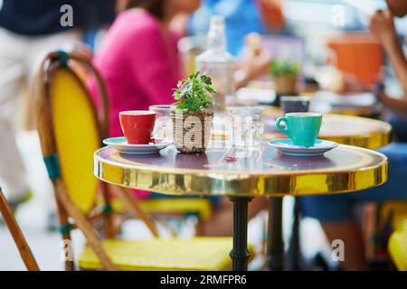 Two colorful coffee cups and green plant on the table of an outdoor Parisian cafe Stock Photo