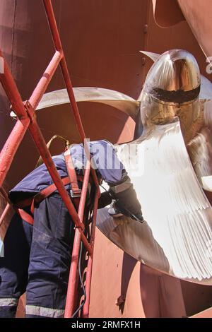 man repairing a ship propeller using a handheld saw .propeller ship maintenance. dry dock. Stock Photo