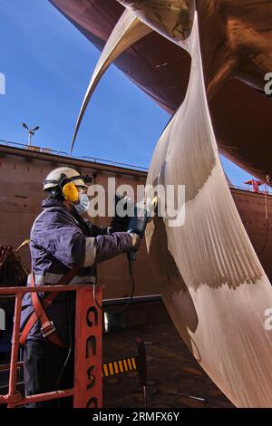 man repairing a ship propeller using a handheld saw .propeller ship maintenance. dry dock. Stock Photo