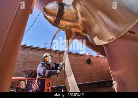 man repairing a ship propeller using a handheld saw .propeller ship maintenance. dry dock. Stock Photo