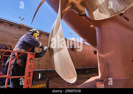 man repairing a ship propeller using a handheld saw .propeller ship maintenance. dry dock. Stock Photo