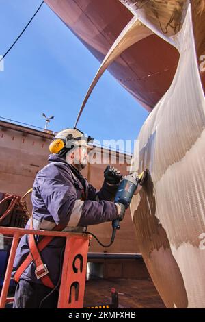 man repairing a ship propeller using a handheld saw .propeller ship maintenance. dry dock. Stock Photo