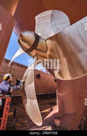 man repairing a ship propeller using a handheld saw .propeller ship maintenance. dry dock. Stock Photo