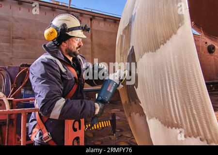 man repairing a ship propeller using a handheld saw .propeller ship maintenance. dry dock. Stock Photo