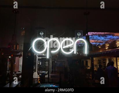 "Open" neon sign hanging in a restaurant window. Stock Photo