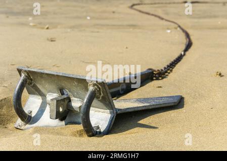 A rusty anchor on the beach somewhere near Arcachon in France. Concept for a safe harbour and security. Copyspace. Stock Photo