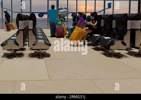 Son and father of multiethnic homoparental family enjoy sunset in international airport lounge as passengers and crew wear protective masks in times o Stock Photo