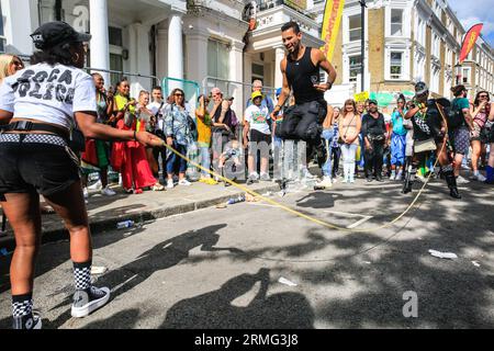London, UK. 28th Aug, 2023. A young man manages over 40 jumps. The Notting Hill 'Soca Police' host a rope jumping competition. After the parade, crowds gather in the street and around the many sound systems and food stalls on Carnival Monday. Up to two million people are expected to celebrate the carnival this Bank Holiday Weekend participating or watching. Credit: Imageplotter/Alamy Live News Stock Photo