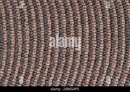 Dark relief texture of rolled up carpet edge for unusual background. Close up of brown pattern of synthetic tight knitted jute rows. Concept of textur Stock Photo