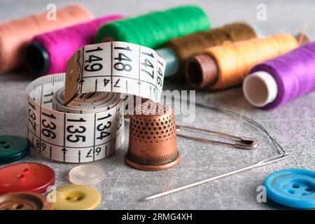 Sewing kit of needle, thimble, thread and measuring meter.On gray concrete table top Stock Photo