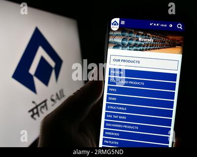 Person holding cellphone with webpage of company Steel Authority of India Limited (SAIL) on screen with logo. Focus on center of phone display. Stock Photo