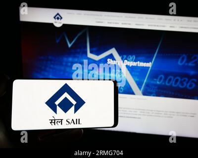 Person holding mobile phone with logo of company Steel Authority of India Limited (SAIL) on screen in front of web page. Focus on phone display. Stock Photo