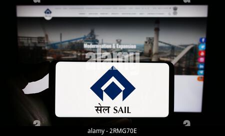 Person holding smartphone with logo of company Steel Authority of India Limited (SAIL) on screen in front of website. Focus on phone display. Stock Photo