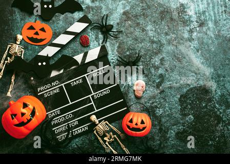 Halloween movies concept. Movie clapperboard with funny halloween pumpkin,skeletons and spiders over grunge background. Halloween concept background Stock Photo