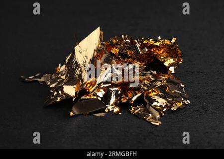 Pieces of edible gold leaf on light blue background, flat lay