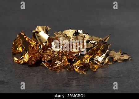 Pieces of edible gold leaf on light blue background, flat lay