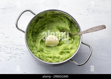 Delicate mashed potatoes with green peas, flavored with butter on a light blue background. delicious homemade food. Stock Photo