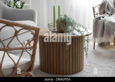 Coffee table with aroma candles and houseplant in bright living room Stock Photo