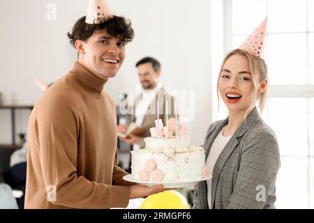 Young man greeting his colleague with Birthday cake at party in office Stock Photo