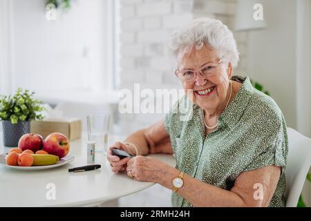 Portrait Using Glucometer Portrait of diabetic senior patient checking her blood sugar level with ...