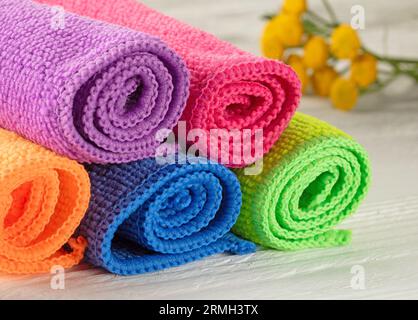 Bright multicolored kitchen napkins rolled up in rolls on a wooden table. Stock Photo
