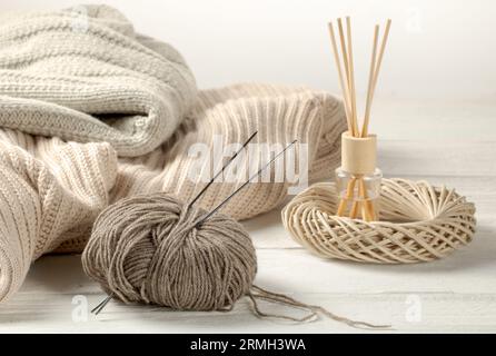 Cozy home interior - knitted things and balls of woolen threads on a wooden table. Stock Photo