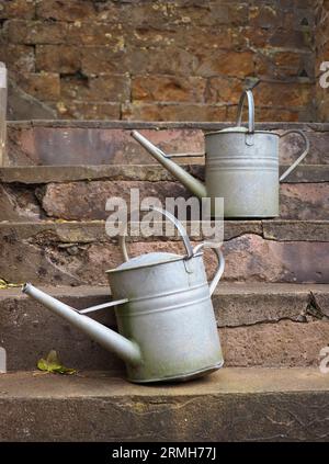 An antique watering cans on stone steps, Upton House, Warwickshire Stock Photo