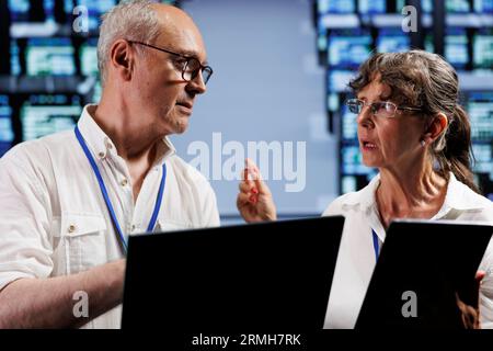 Competent electricians monitoring supercomputers, optimizing them for data processing requirements of AI applications. Certified wiremen working in server room used for neural network training Stock Photo