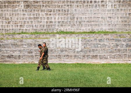 Belizean soldiers walk past Caana ('Sky Place'), the largest temple at Caracol, a Mayan city ruins dating back to 1200 BCE located in Belize Stock Photo